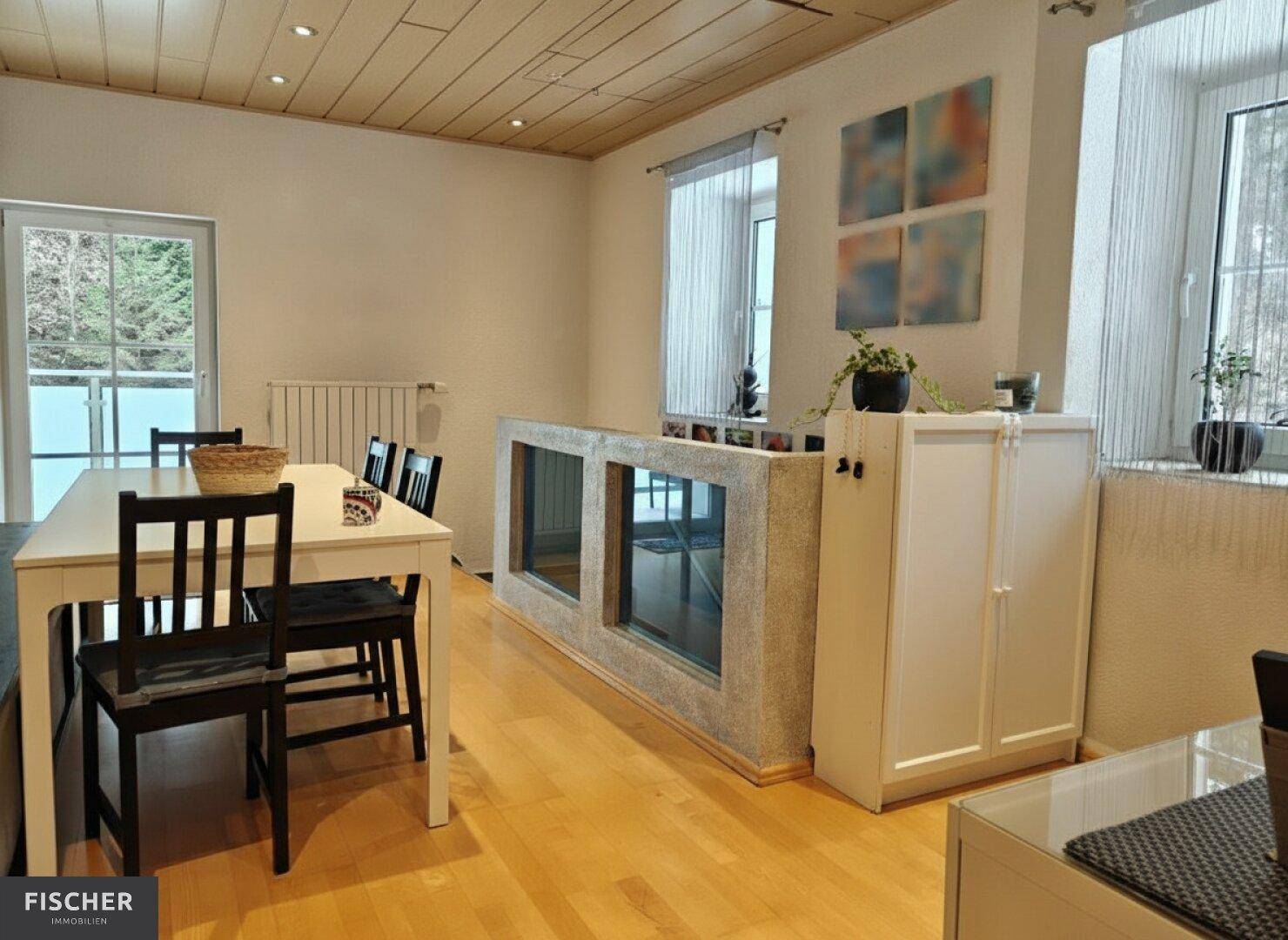 Essbereich mit Holztisch, Stühlen und einem großen Aquarium als Raumteiler.