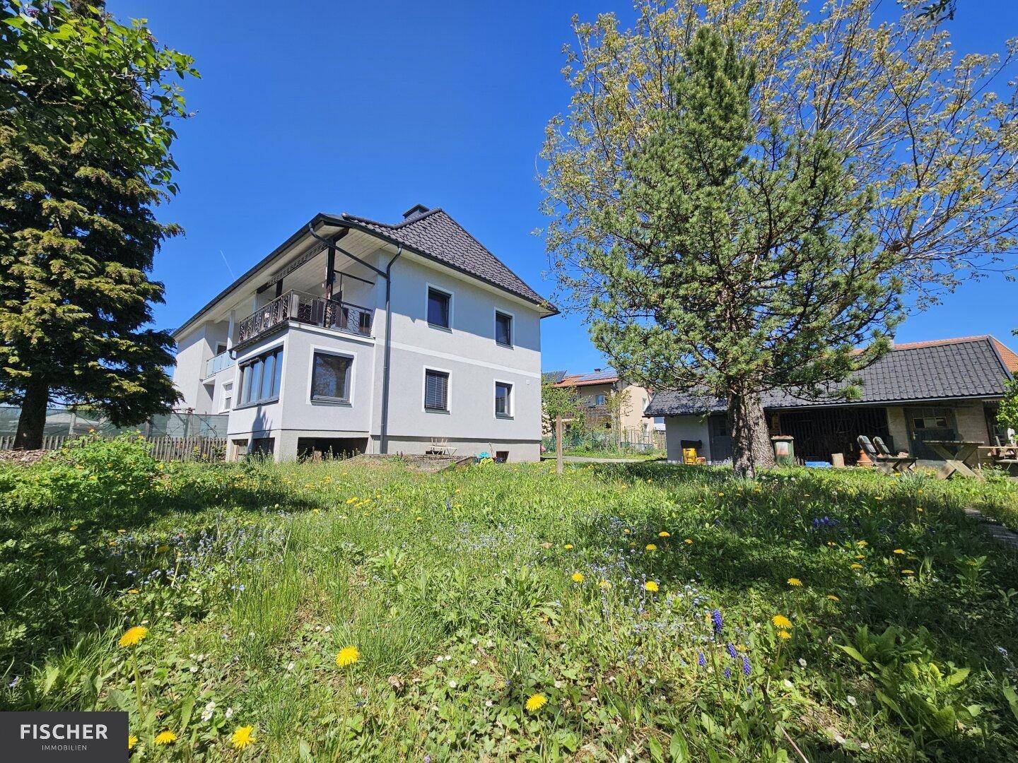 Ansicht des Wohnhauses von der Gartenseite mit Balkon und gepflegter Umgebung.