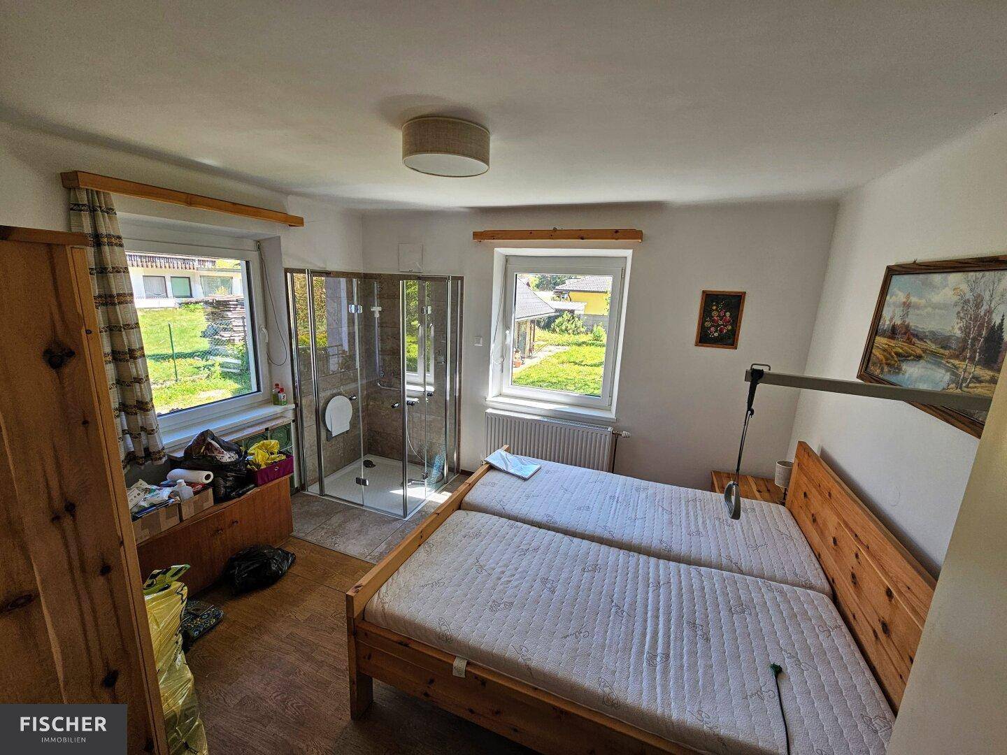 Schlafzimmer mit zwei Einzelbetten und integrierter Duschkabine, hell und funktional eingerichtet.