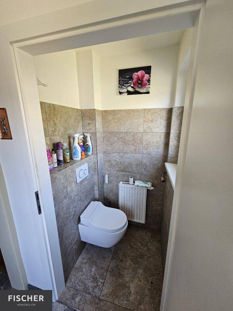 Gäste-WC mit Wand-WC und Fliesen an den Wänden, einfach und funktional.