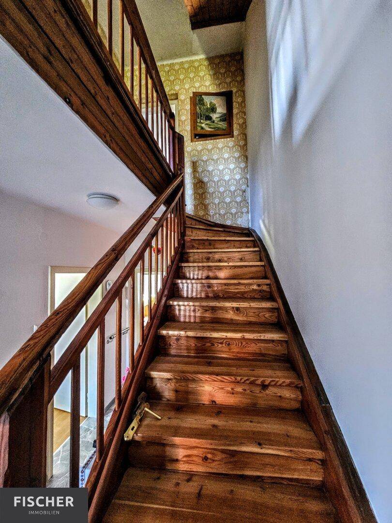 Rustikale Holztreppe mit Geländer, die die verschiedenen Etagen des Hauses verbindet.