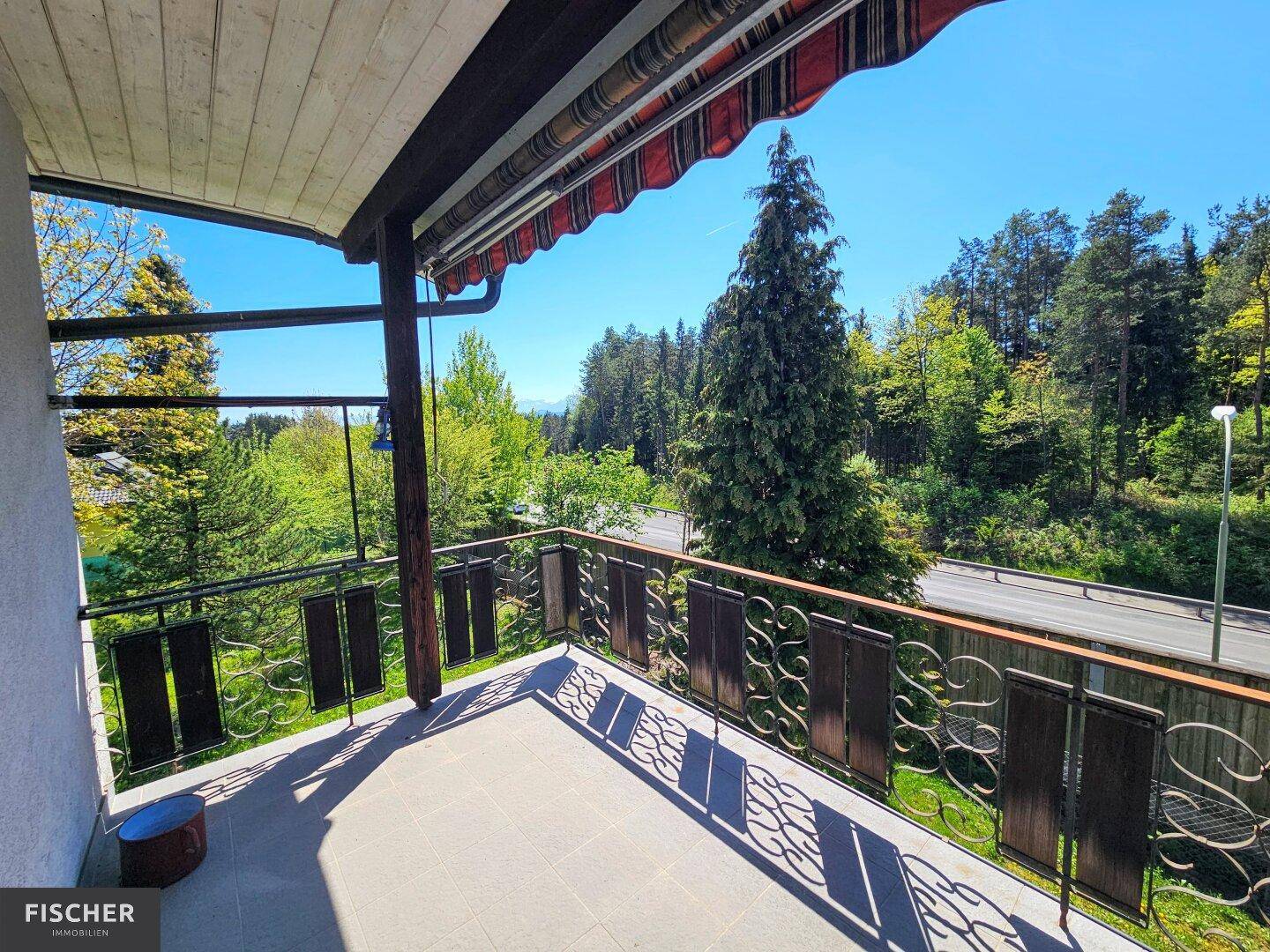 Geräumiger Balkon mit Fliesenboden und schöner Aussicht auf die umliegende Natur und Straße.