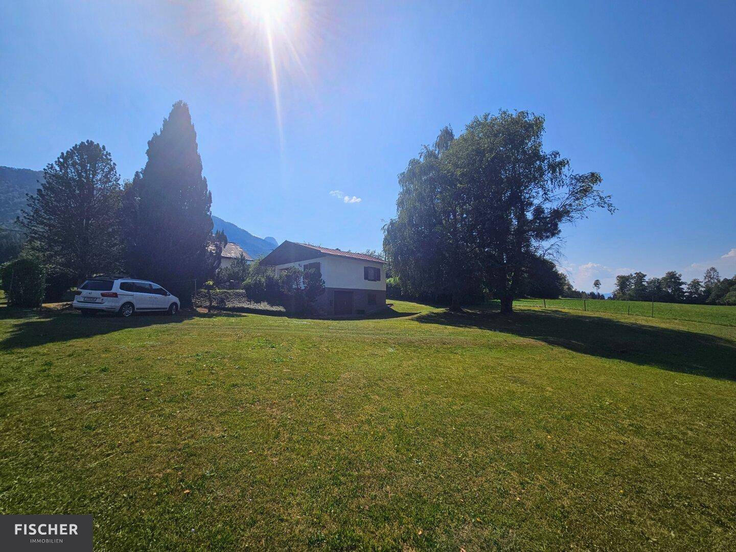 Weitläufige Rasenfläche mit freistehendem Haus und Blick auf die umliegende Landschaft.