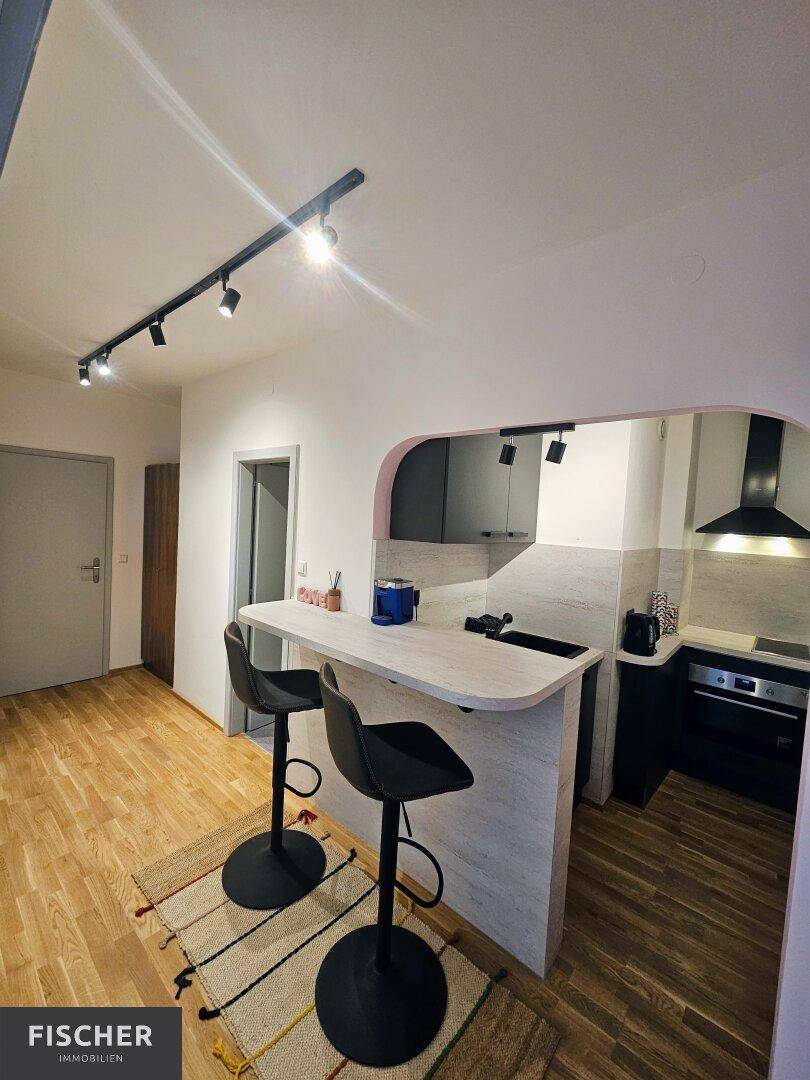 Moderne Küchenzeile mit Frühstücksbar und Barhockern, ausgestattet mit praktischer Beleuchtung.