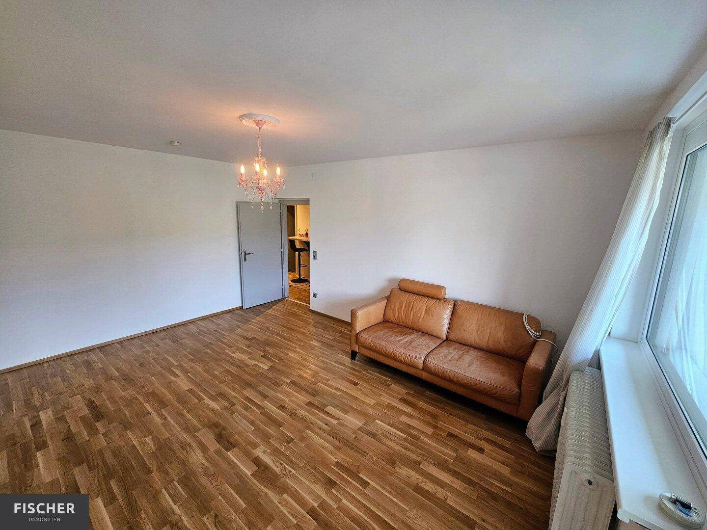 Geräumiges Wohnzimmer mit Holzboden und einem bequemen Ledersofa, ideal für Entspannung.