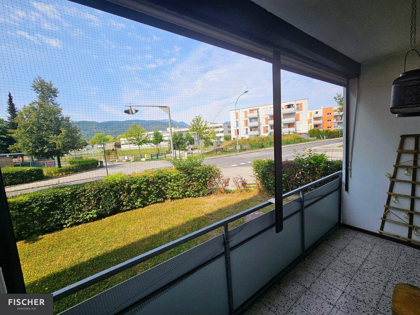 Balkon mit Blick auf die Straße und umliegende Gebäude, geschützt durch ein Netz.