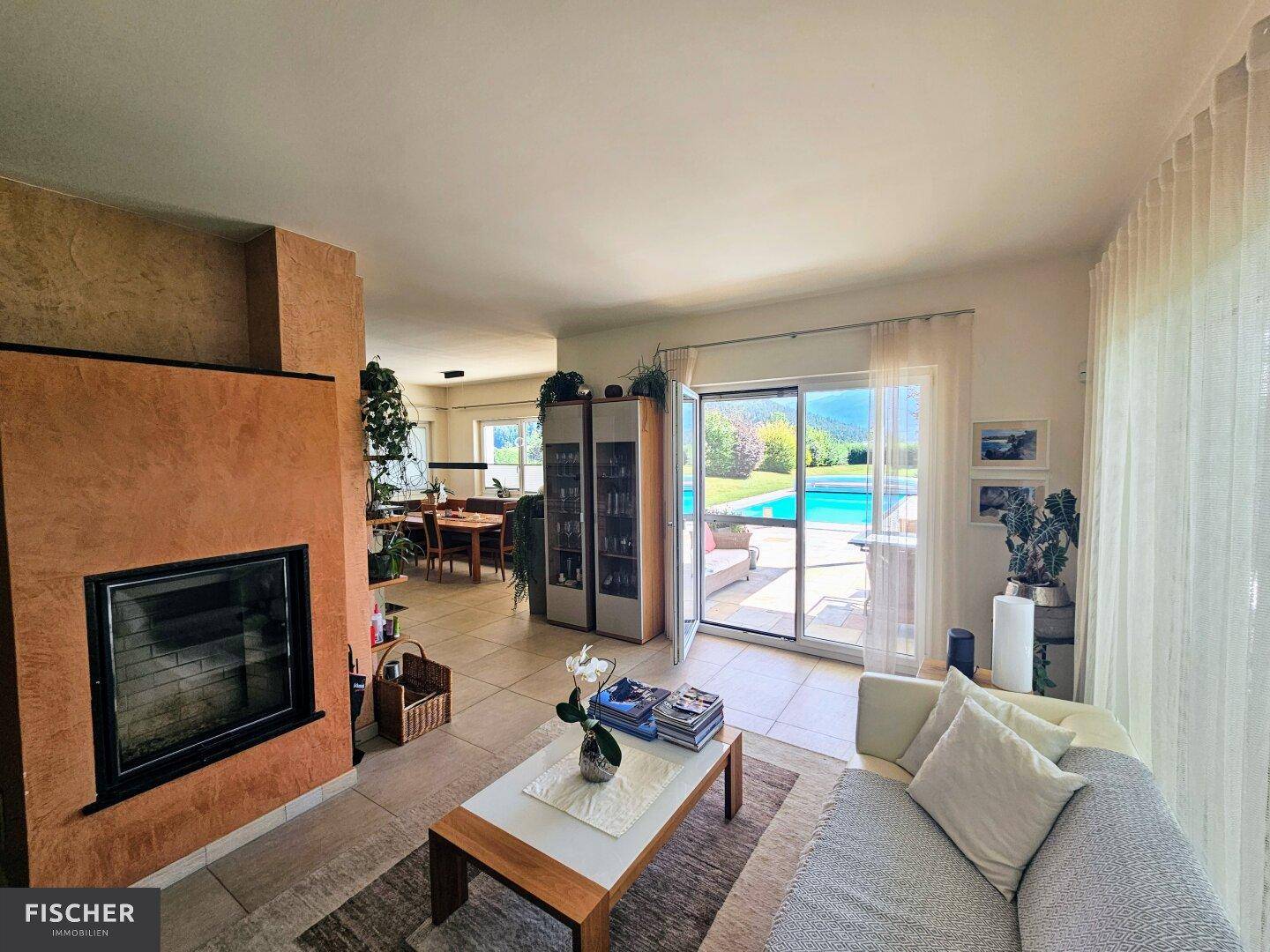 Gemütliches Wohnzimmer mit Kamin und Zugang zur Terrasse mit Poolblick.