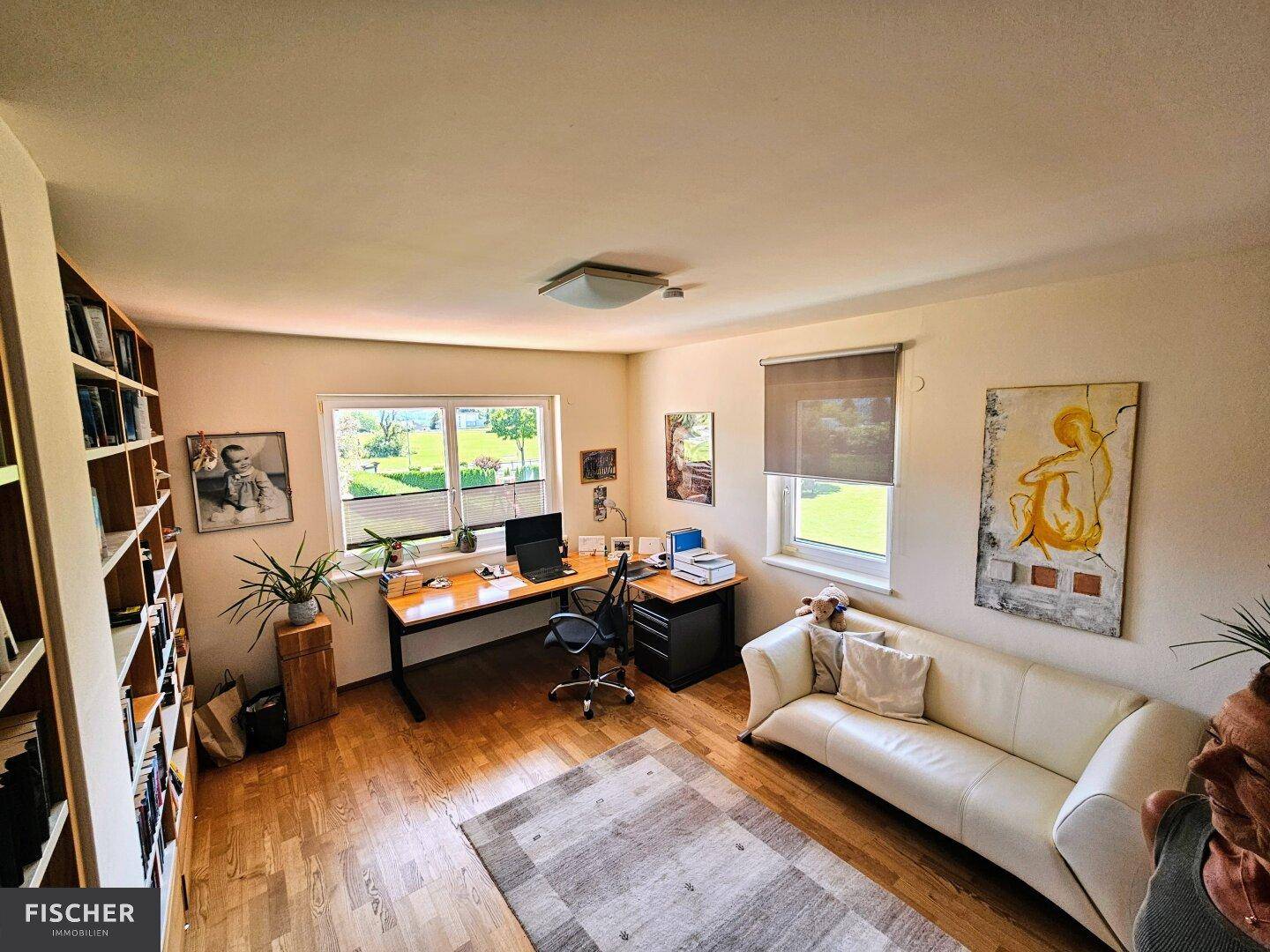 Helles Arbeitszimmer mit großem Schreibtisch, Bücherregalen und Blick ins Grüne.