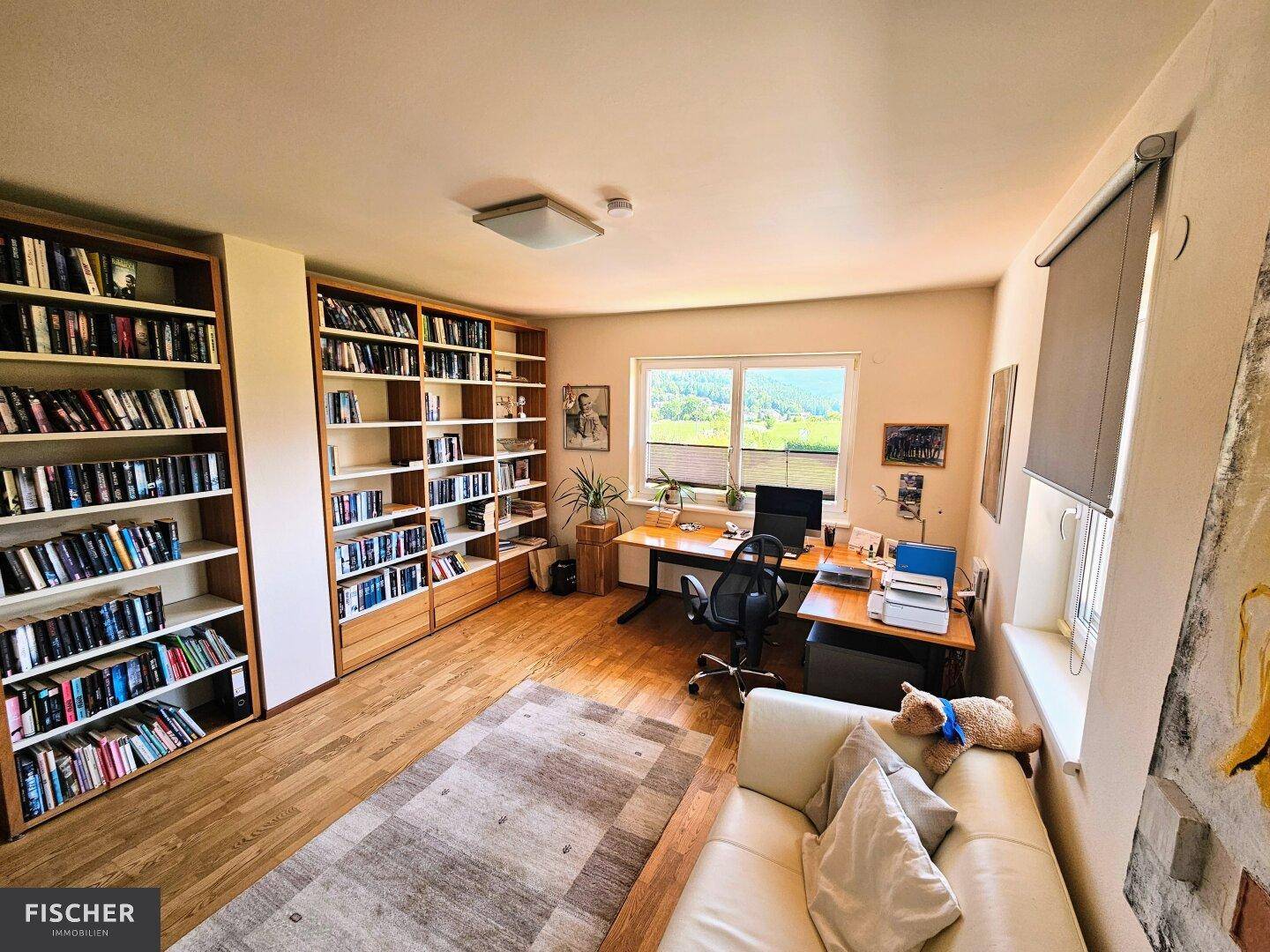Geräumiges Arbeitszimmer mit umfangreichen Bücherregalen und Blick auf die Landschaft.