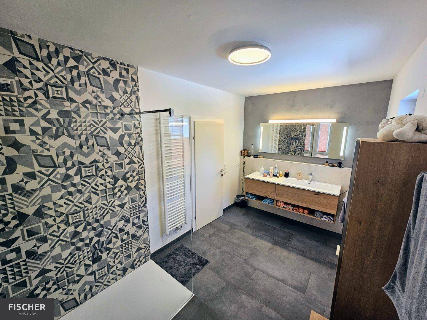 Modernes Badezimmer mit großer Dusche, Doppelwaschbecken und stilvollen Fliesen.