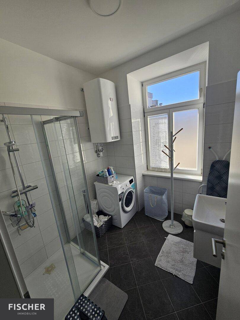 Modernes Badezimmer mit Dusche, Waschmaschine und Fenster für Tageslicht.