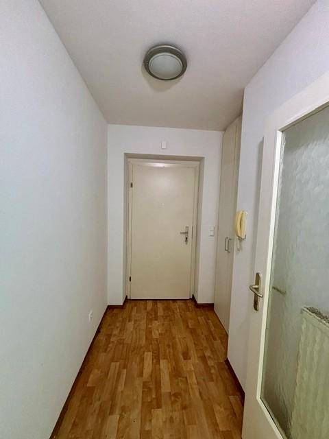 Eingangsbereich mit Laminatboden und einer Gegensprechanlage neben der Haustür.