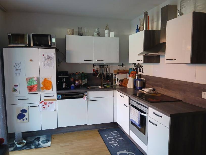 Funktionale Küche mit weißen Schränken, Holzarbeitsplatte und integrierten Haushaltsgeräten.