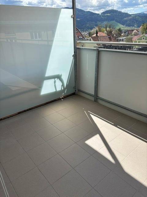Heller Balkon mit Fliesenboden und Glasbrüstung, bietet einen weiten Blick auf die Umgebung.