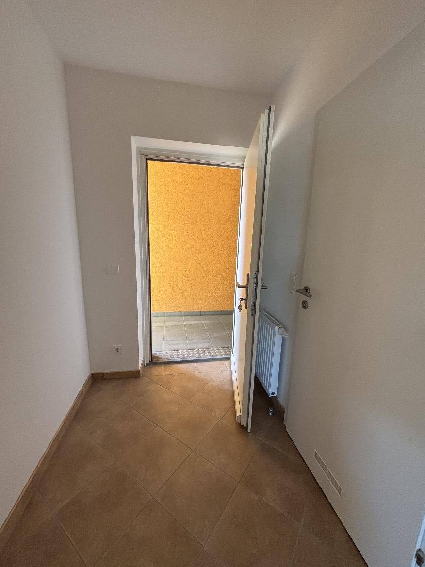 Heller Eingangsbereich einer Wohnung mit Fliesenboden und Blick in den Hausflur.
