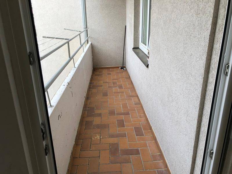 Schmaler Balkon mit Terrakotta-Fliesen und Metallgeländer.