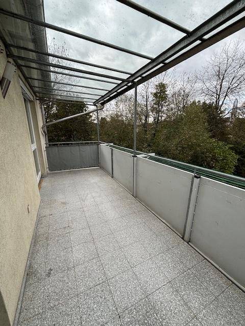 Überdachter Balkon mit Fliesenboden und Blick ins Grüne, ideal zum Entspannen.