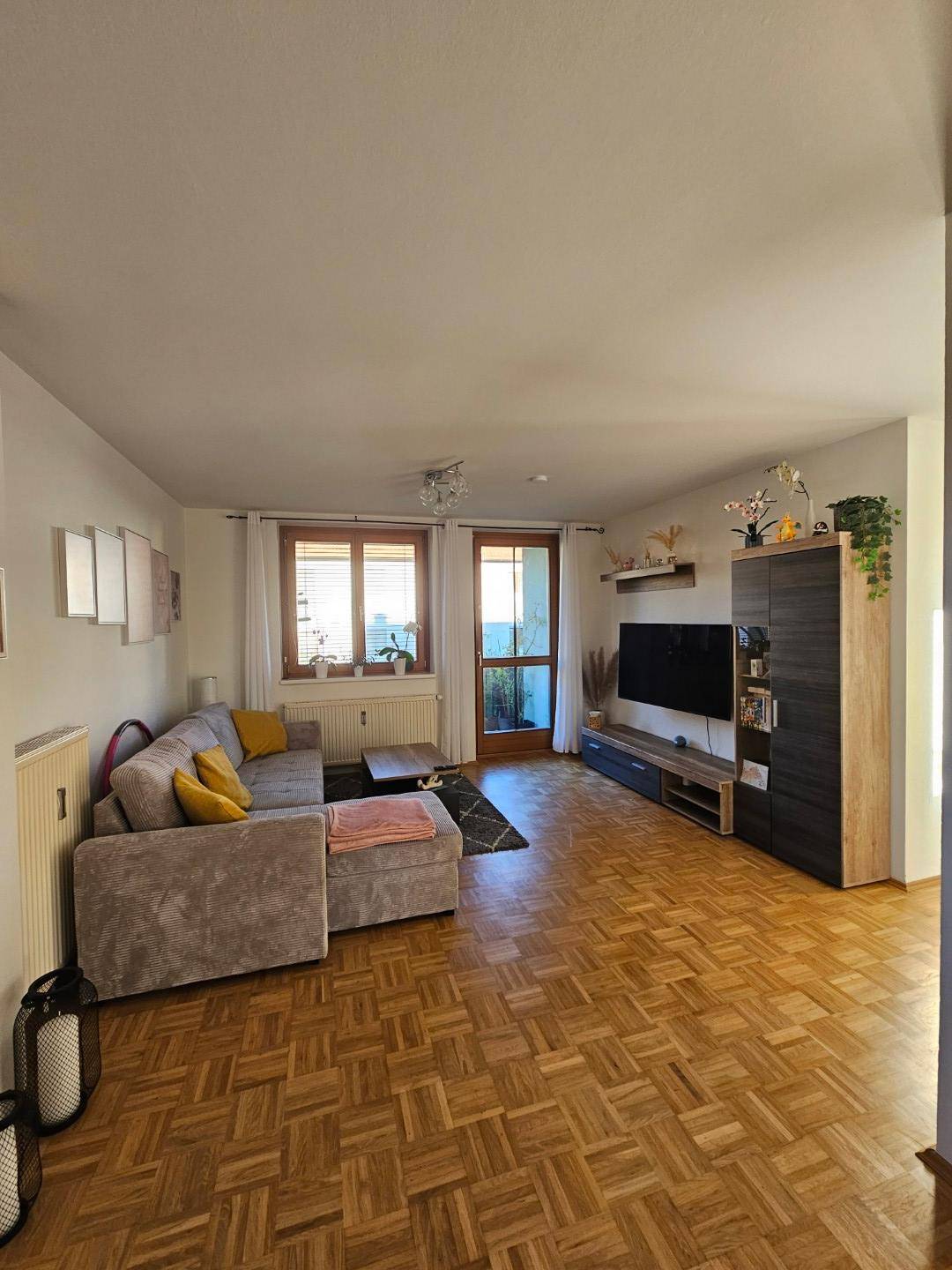 Geräumiges Wohnzimmer mit Sofa, TV-Möbel und Zugang zum Balkon.