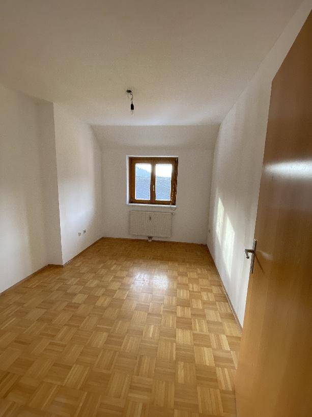 Gemütliches Schlafzimmer mit Parkettboden und Fenster im Dachgeschoss.