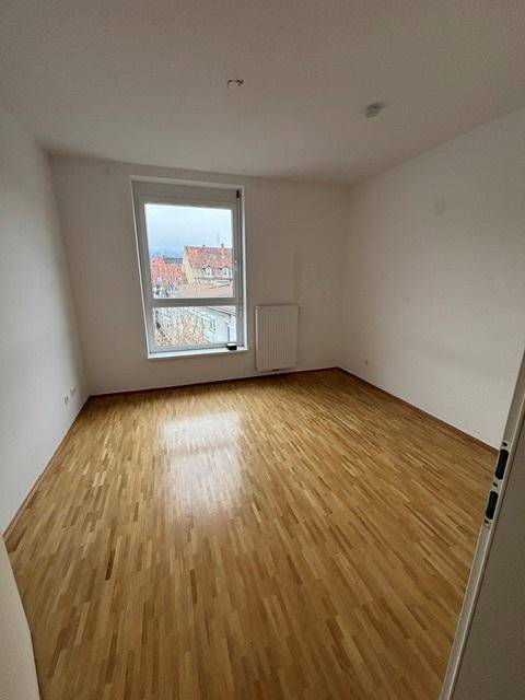 Geräumiges Schlafzimmer mit Parkettboden und großem Fenster, das einen weiten Blick bietet.