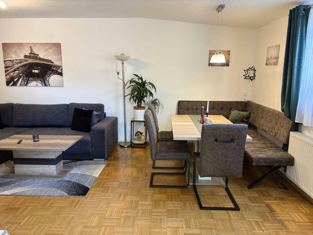 Geräumiger Wohn-Essbereich mit großem Sofa, Esstisch und Parkettboden, ideal für gesellige Abende.