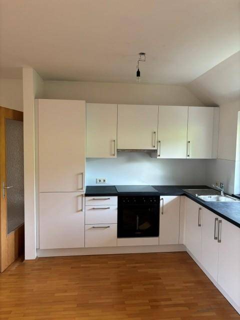 Funktionale Küche mit integriertem Kühlschrank, Backofen und ausreichend Stauraum in den Oberschränken.