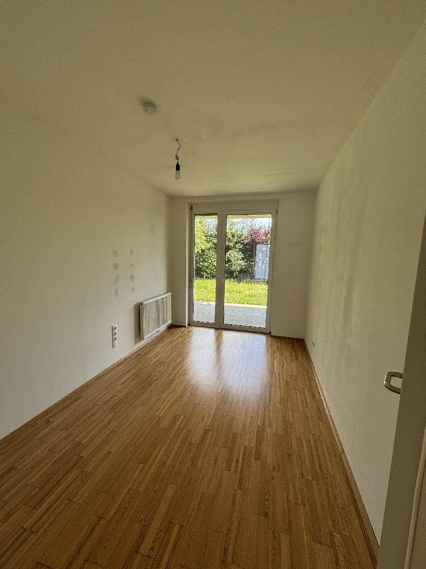 Helles Schlafzimmer mit Holzparkett und direktem Zugang zu einem Außenbereich.