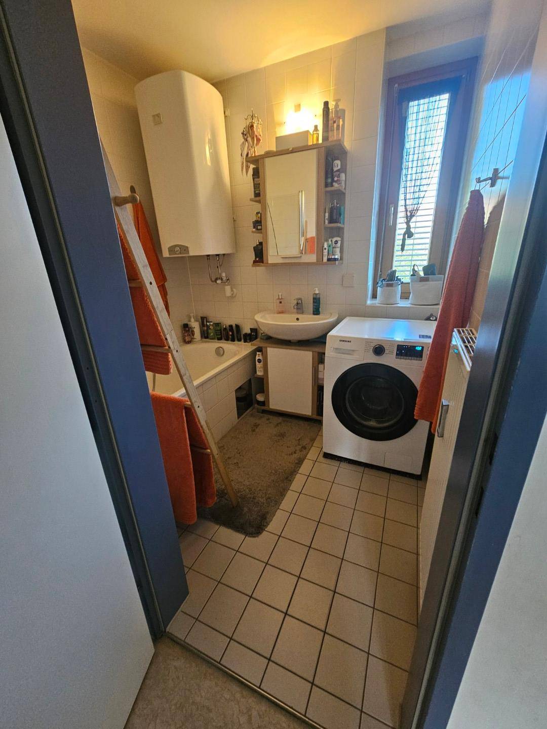 Funktionales Badezimmer mit Badewanne, Waschbecken, Fenster und Waschmaschine.