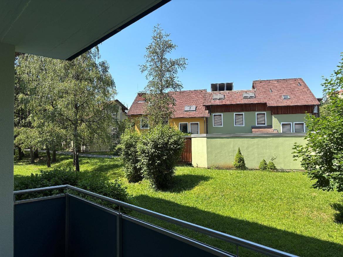 Aussicht von der Loggia auf benachbarte Gebäude und eine gepflegte Grünfläche.