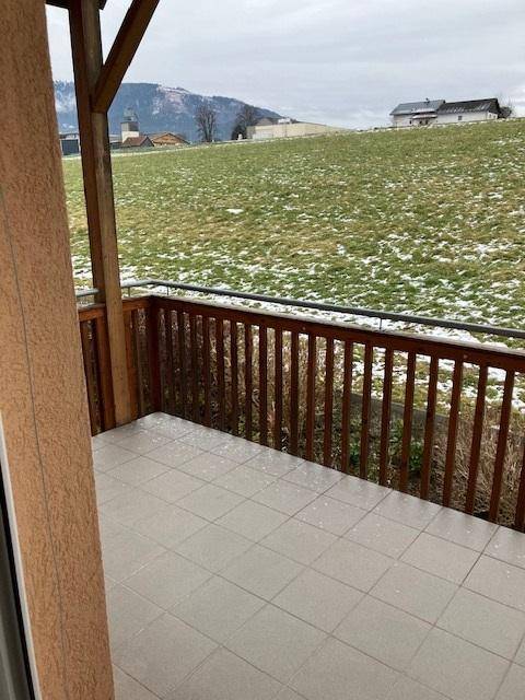 Kleiner Balkon mit Fliesenboden und Holzgeländer, bietet einen weiten Blick ins Grüne.