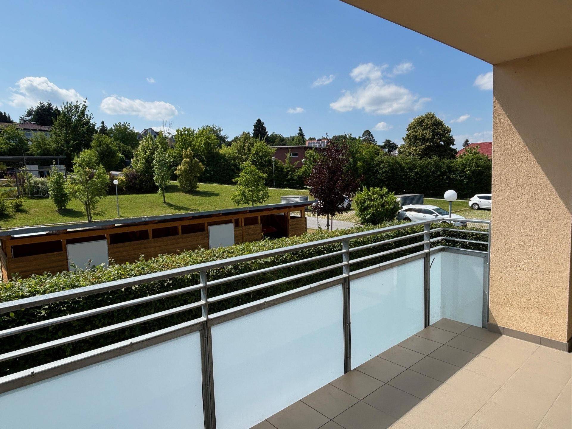 Geräumiger Balkon mit Metallgeländer und weitem Blick auf die grüne Umgebung.