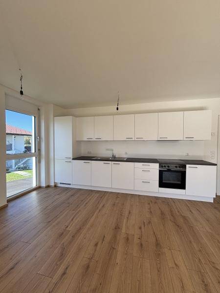 Moderne Einbauküche mit weißen Schränken, dunkler Arbeitsplatte und integriertem Backofen.
