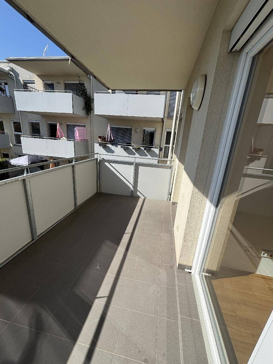 Geräumiger Balkon mit Fliesenboden und Blick auf die umliegenden Gebäude.