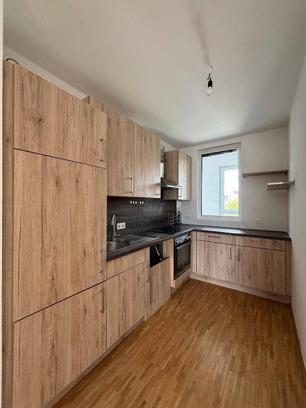Moderne Einbauküche mit Holzfronten, dunkler Arbeitsplatte und Fenster.