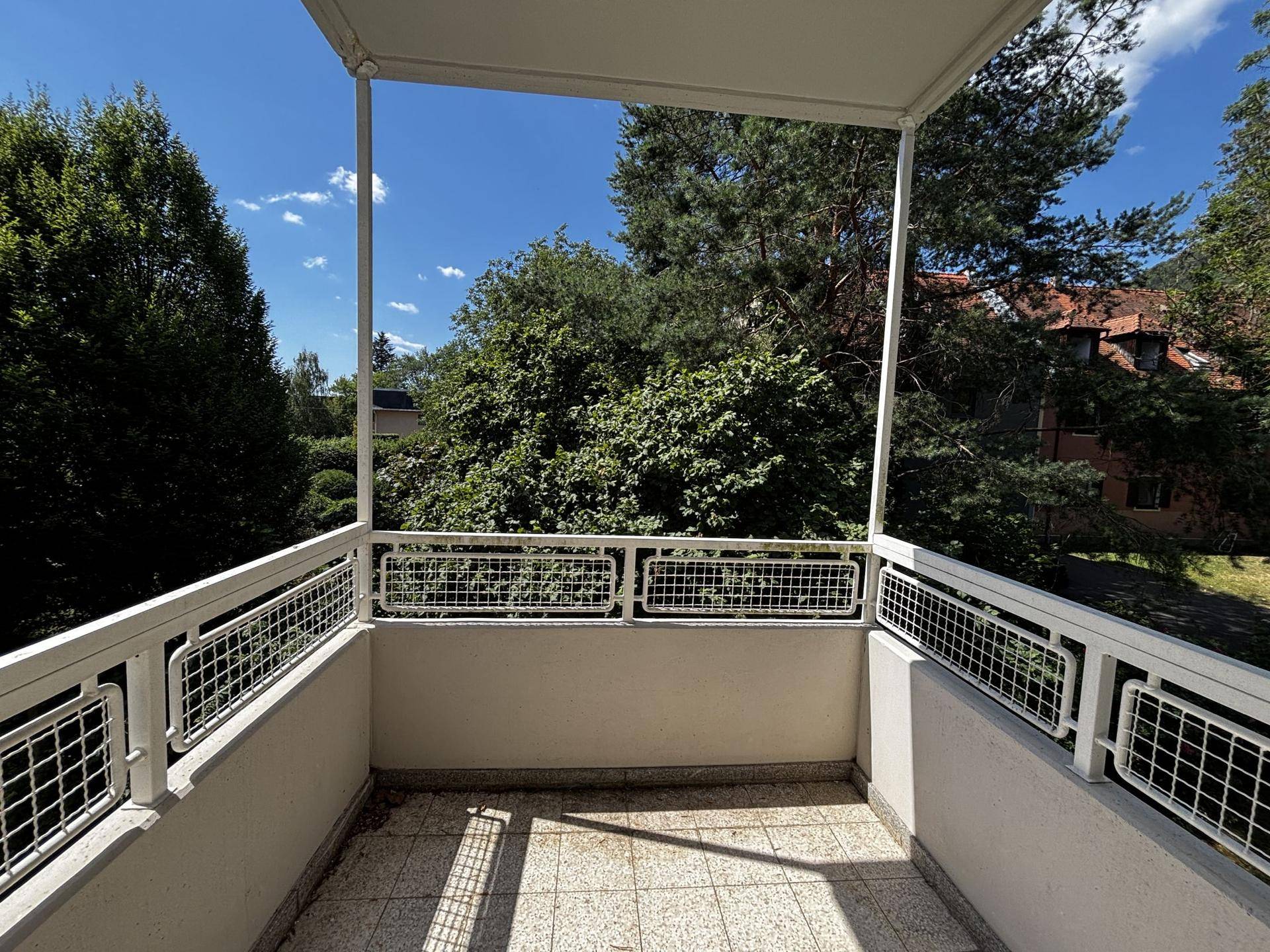 Sonniger Balkon mit Fliesenboden und einem schönen Blick ins Grüne, ideal zum Entspannen.