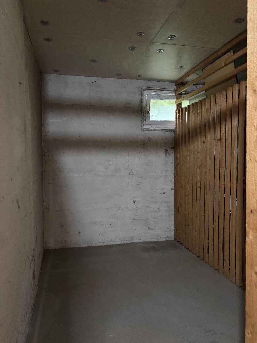 Kellerabteil mit Betonwänden und kleinem Fenster, ideal als zusätzlicher Stauraum.