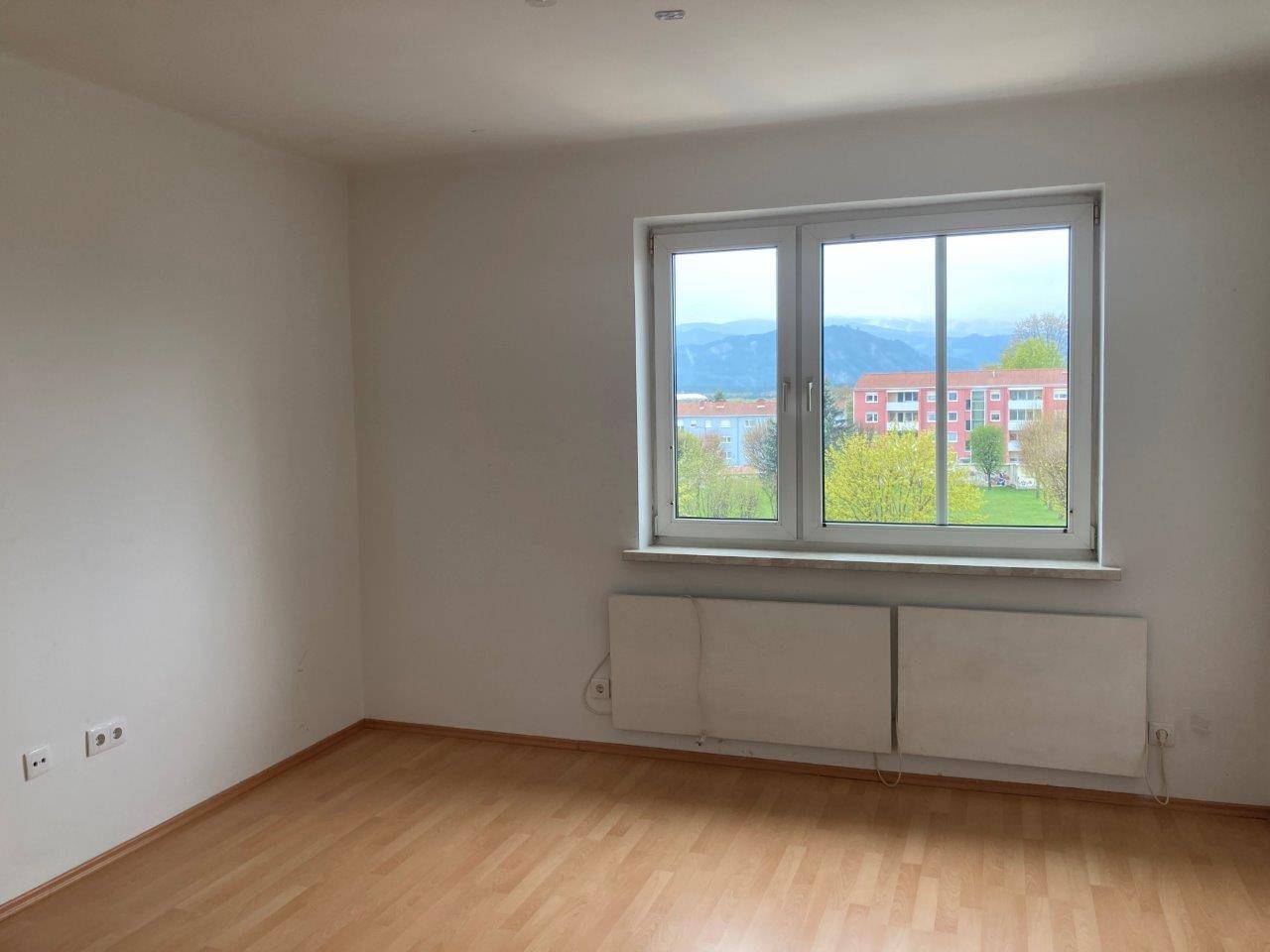 Heller Raum mit Laminatboden und weitem Blick auf die umliegende Landschaft und Berge.