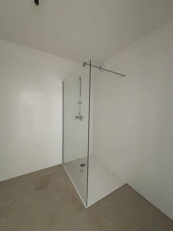 Modernes Badezimmer mit ebenerdiger Dusche und weißen Fliesen, bietet Komfort und Funktionalität.