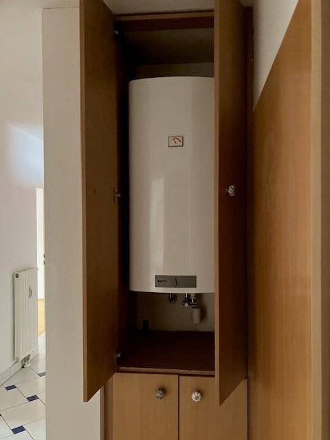 Geöffneter Einbauschrank im Flur mit integriertem Warmwasserboiler.