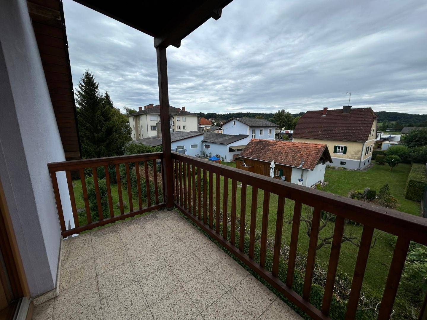 Balkon mit Fliesenboden und Blick auf die umliegende Wohngegend und Gärten.