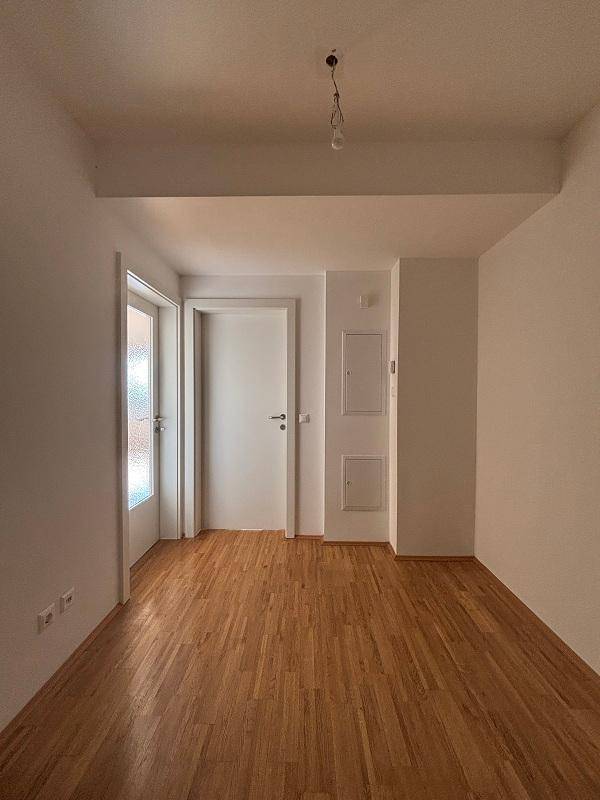 Heller Flur mit Holzboden und weiß gestrichenen Wänden, bereit für die individuelle Gestaltung.