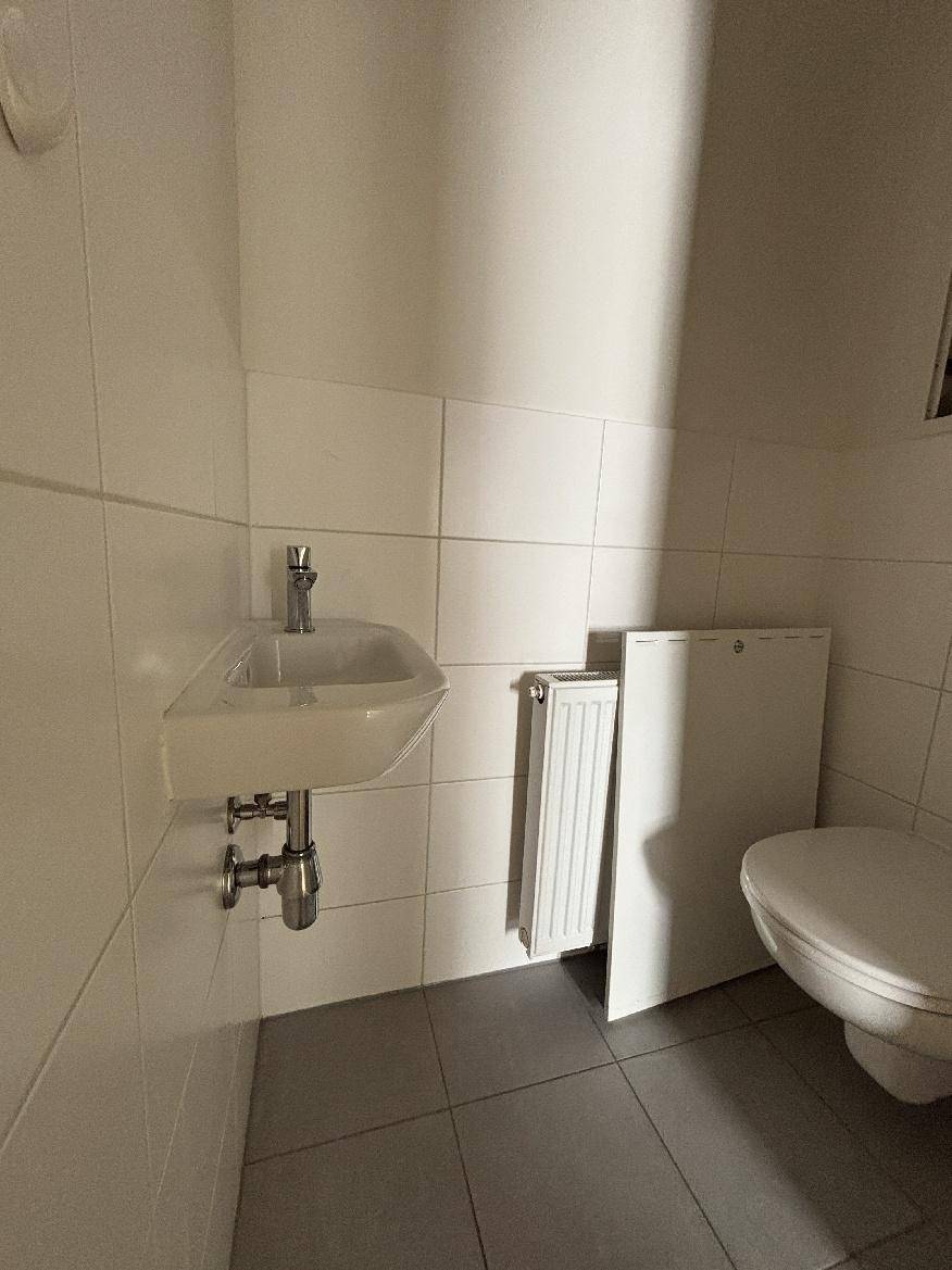 Separates Gäste-WC mit wandhängender Toilette und kleinem Eckwaschbecken.