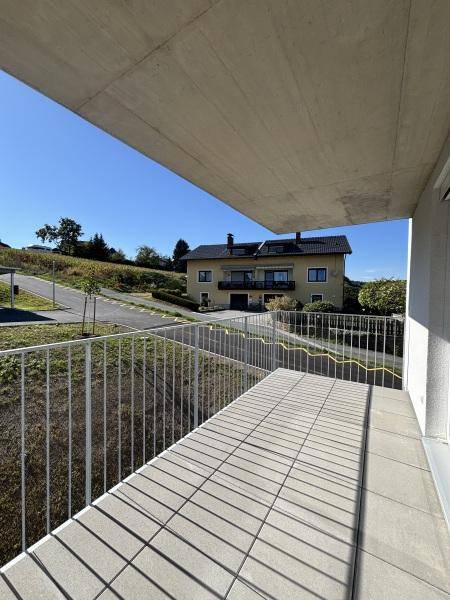 Geräumiger Balkon mit Fliesenboden und Metallgeländer, bietet einen Blick auf die Umgebung.
