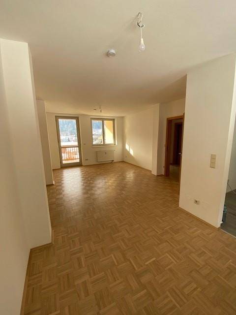 Helles Wohnzimmer mit Parkettboden und Zugang zum Balkon, bietet eine schöne Aussicht.