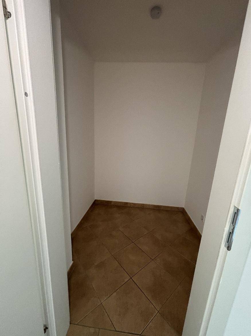 Kleiner Abstellraum mit braunen Fliesen und weißen Wänden, ideal für zusätzlichen Stauraum.