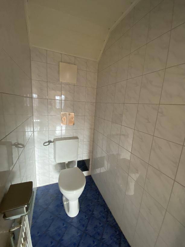 Kleines WC mit Fliesen an Wänden und Boden.