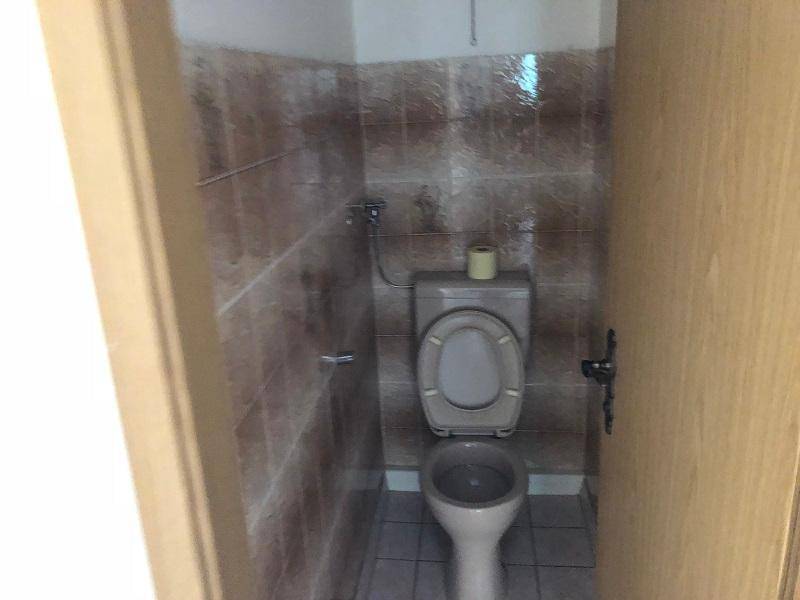 Kleines WC mit Toilette und braunen Fliesen an den Wänden.