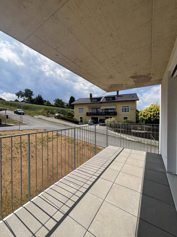 Sonniger Balkon mit Fliesenboden und weitem Blick über die Straße und die Nachbarschaft.