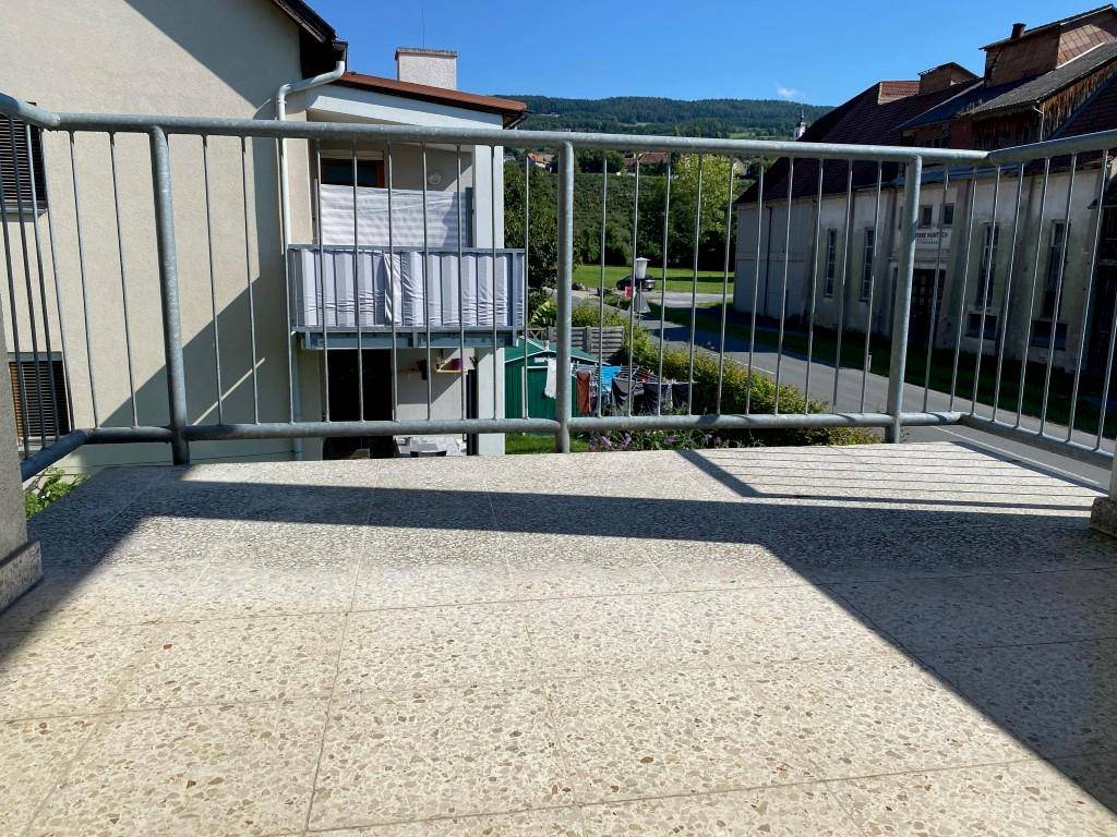 Balkon mit Metallgeländer und weitem Blick auf die umliegende Landschaft und Häuser.