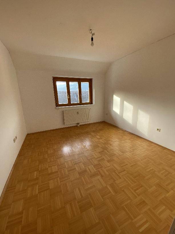Helles Schlafzimmer im Dachgeschoss mit Parkettboden und schrägen Wänden.